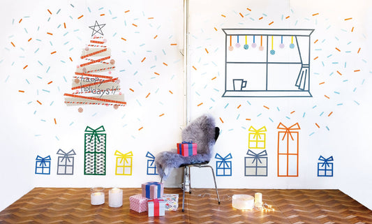 Su una parete bianca, un albero di natale, dei pacchetti regalo e una finestra realizzata con i washi tape
